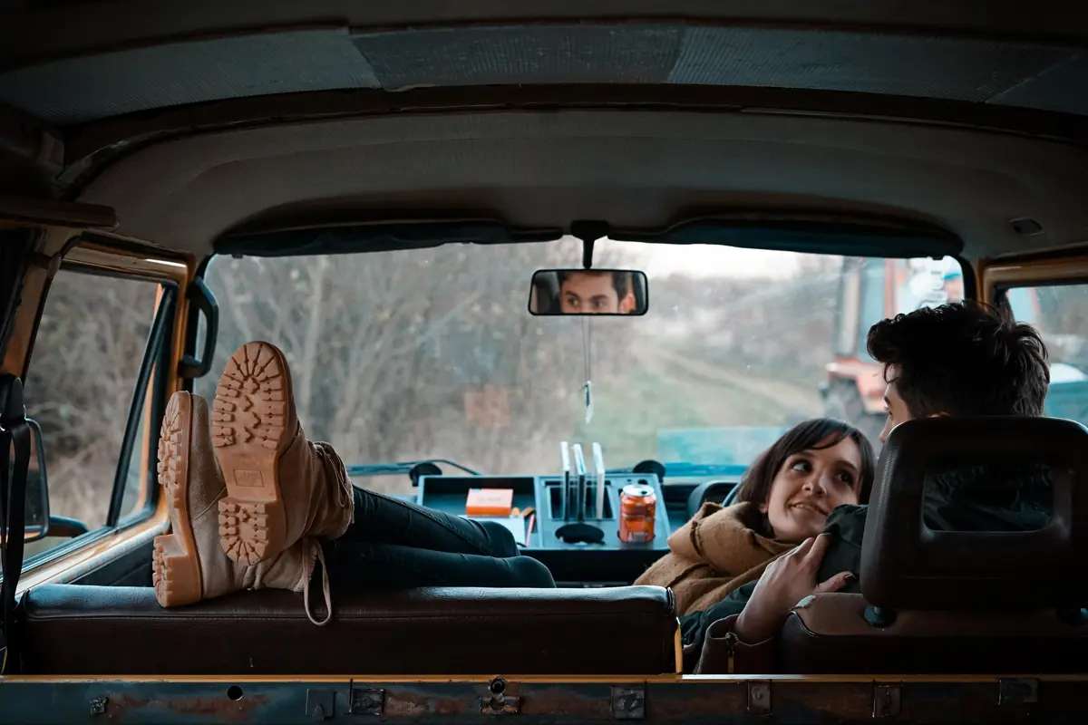 A couple sitting and relaxing in the front seats of a campervan with the women putting her feet up