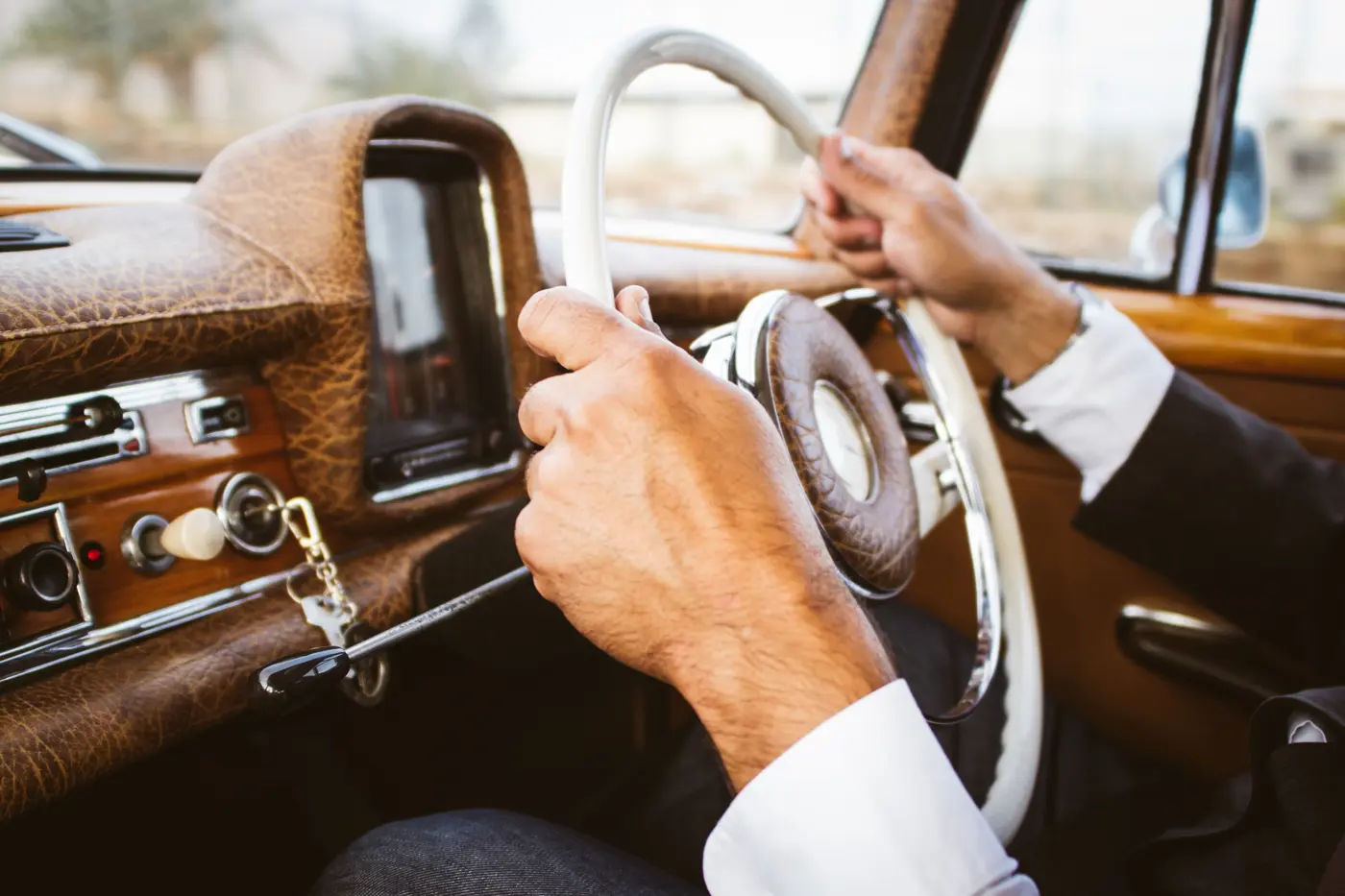 A person driving a classic car with both hands on the wheel