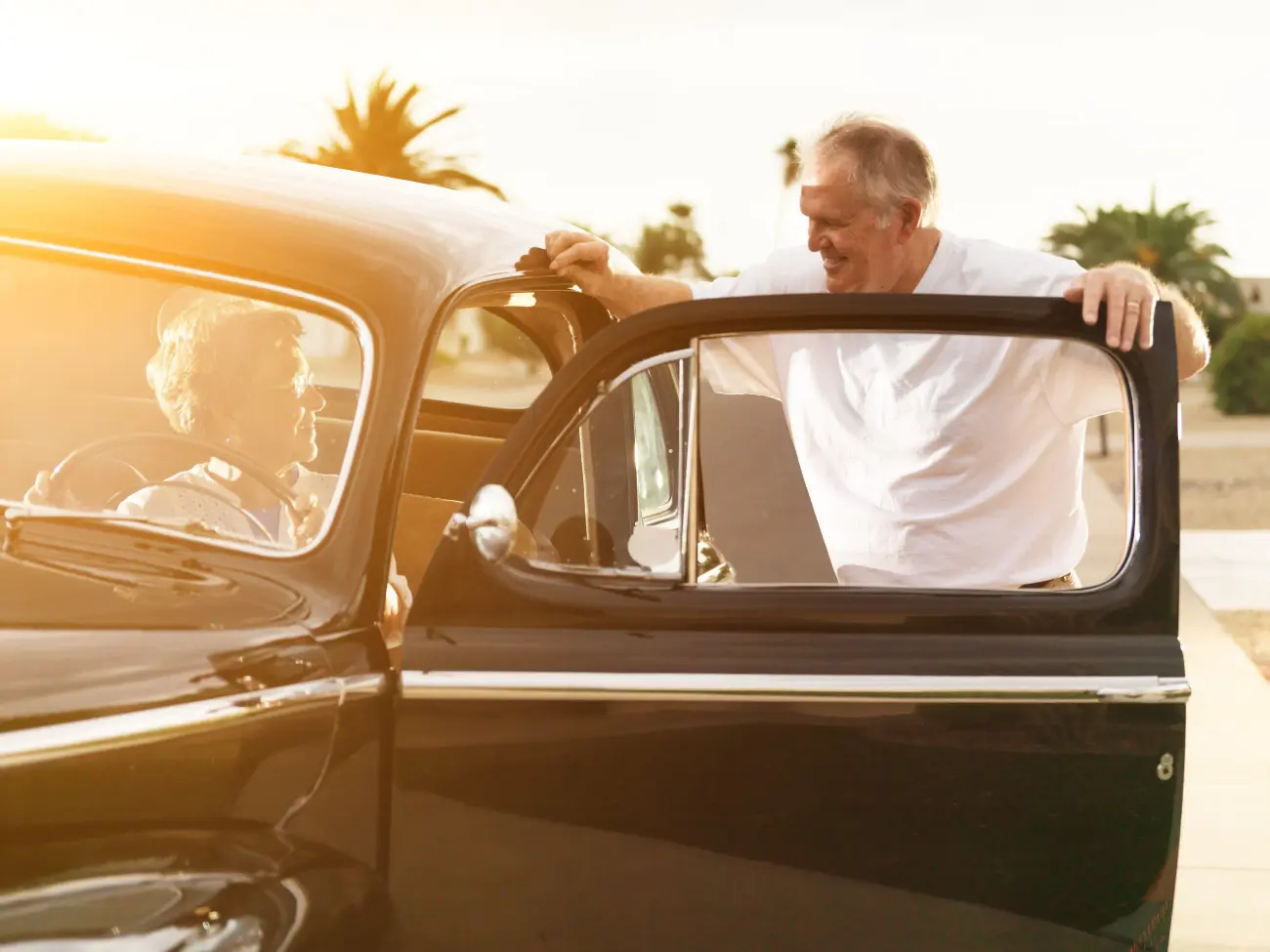 Elderly couple talking in classic car