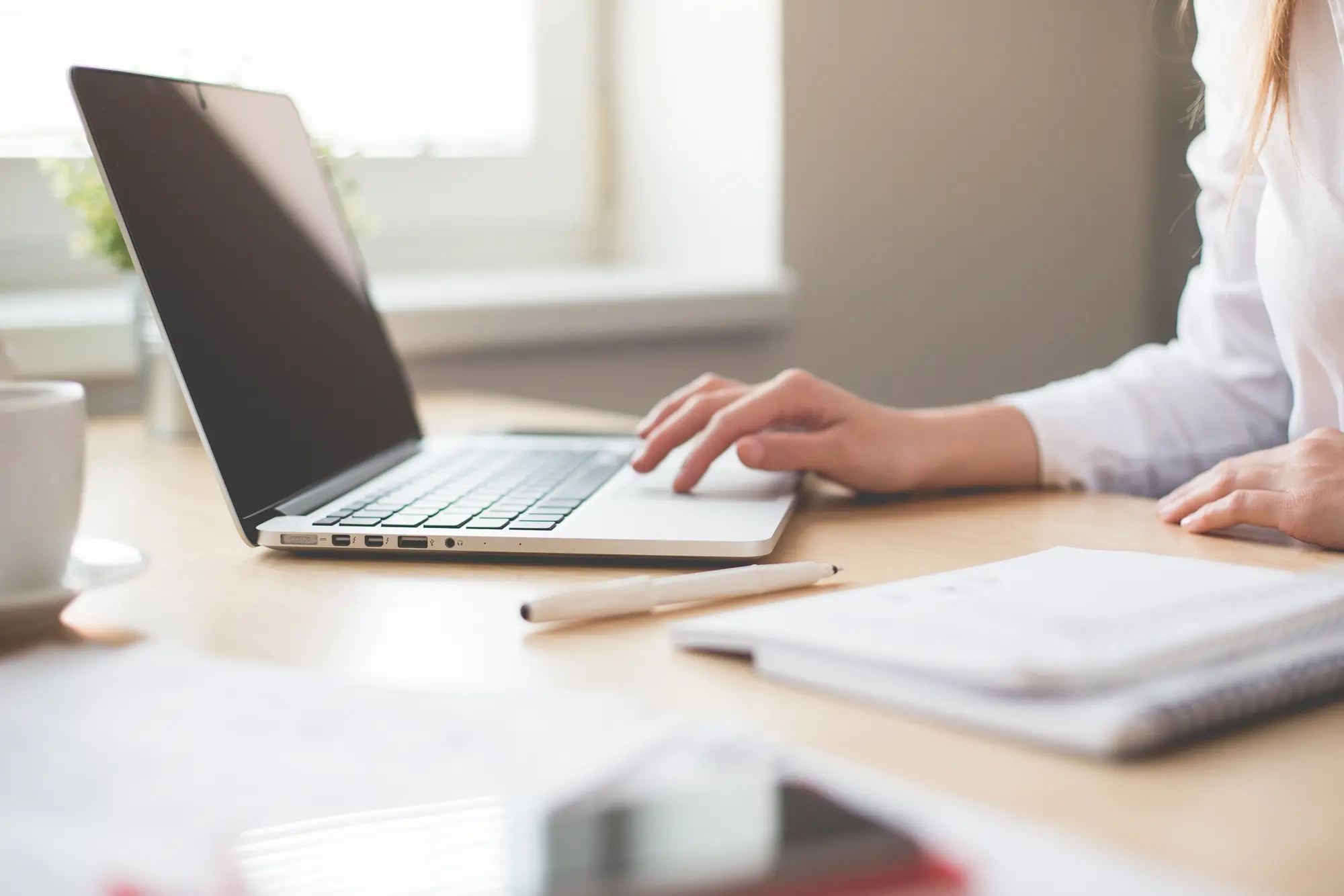 A peson sitting at a desk in their home using a laptop