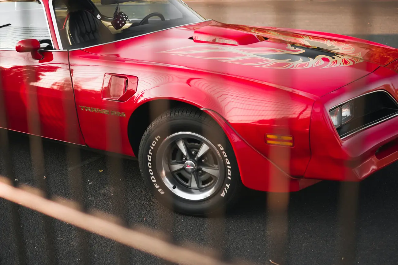 A Pontiac Firebird Trans Am behind a metal fence