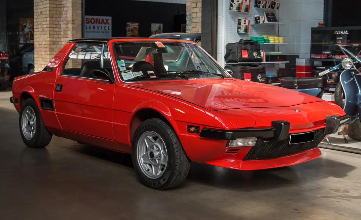 An emaculate red Fiat X1/9 parked in a motor museum