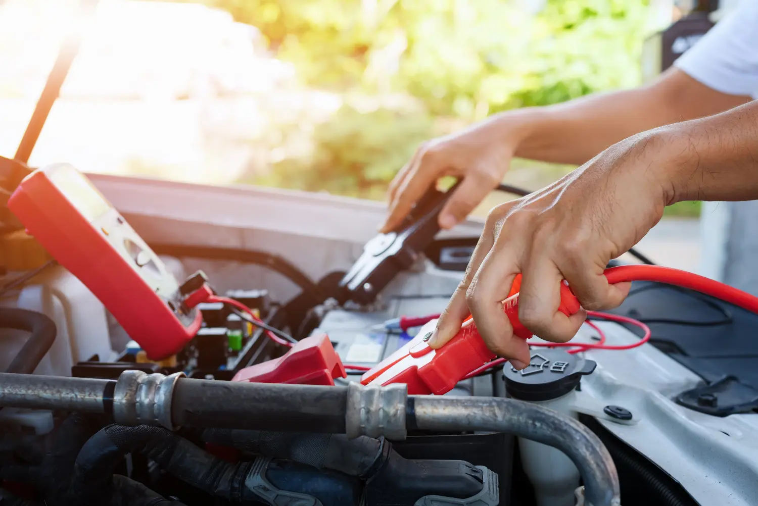 person using jumpstart cables on a car