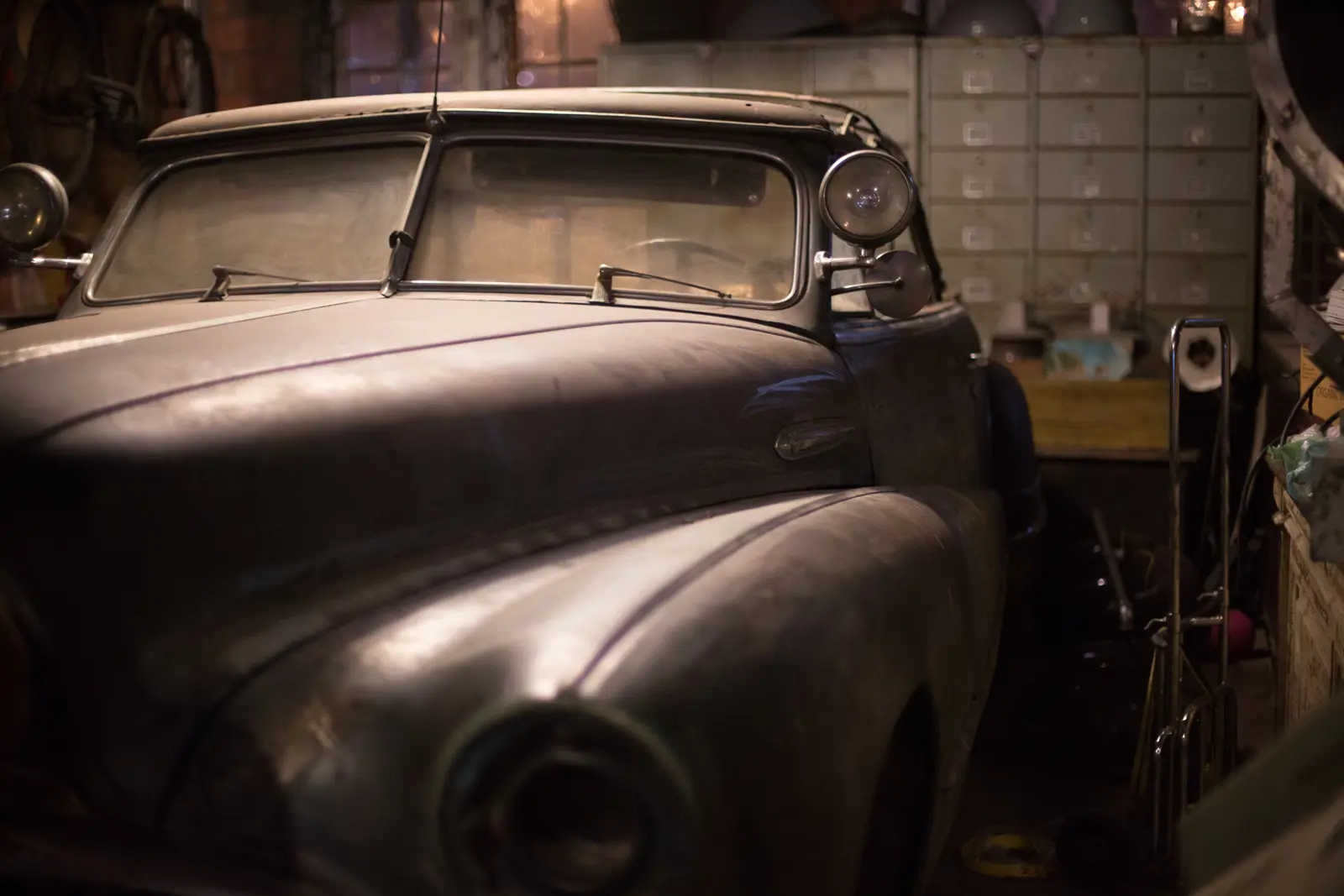 A dusty classic car project stored in a dark garage