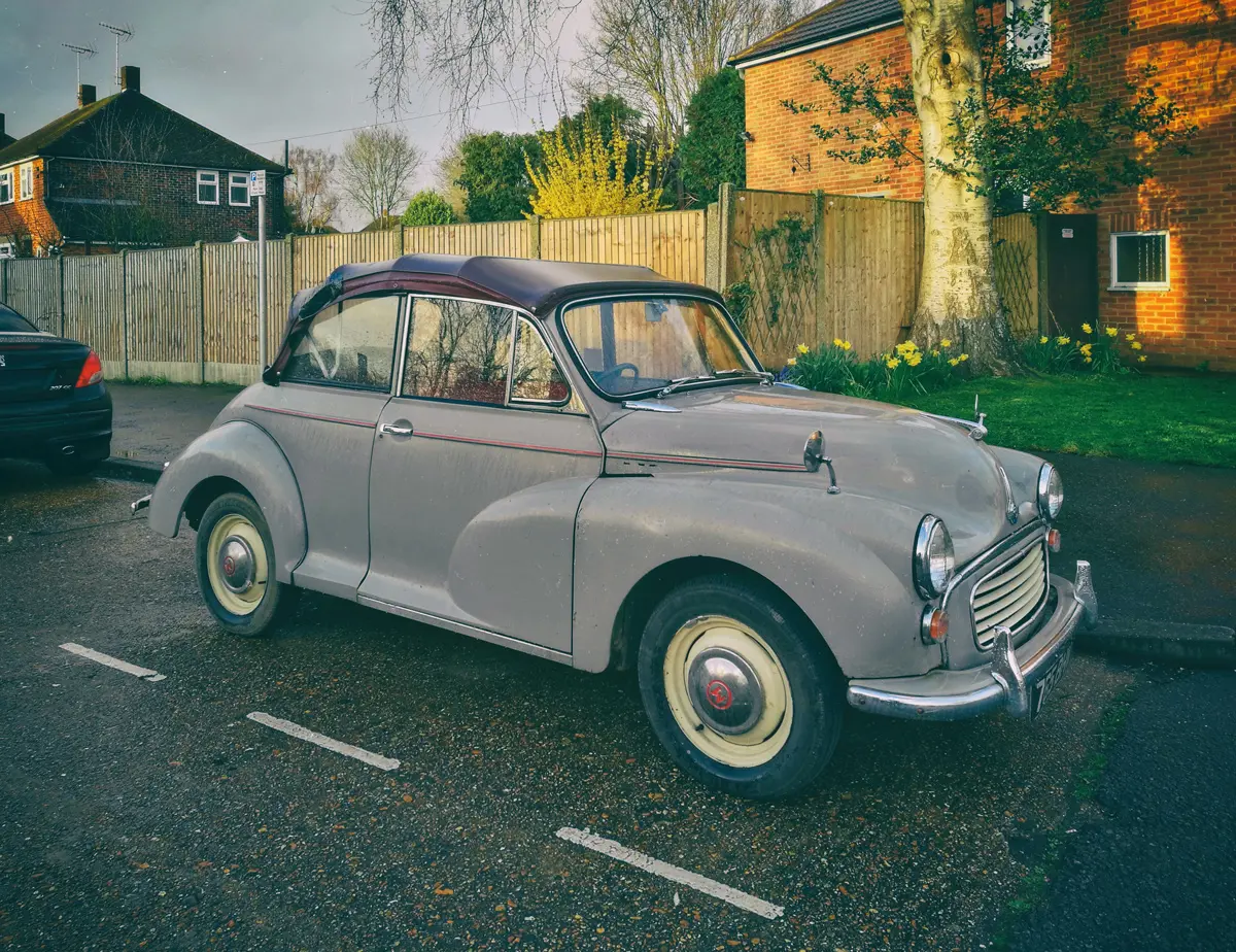 A grey Morris Minor parked outside a house in a residentail parking bay