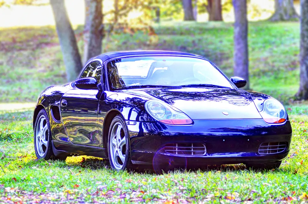 A black Porsche Boxter parked on grass