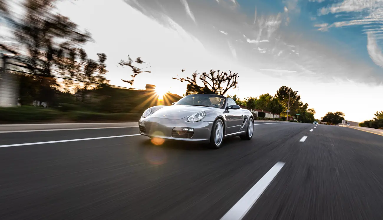 A Porsche Boxter driving at speed on an open road