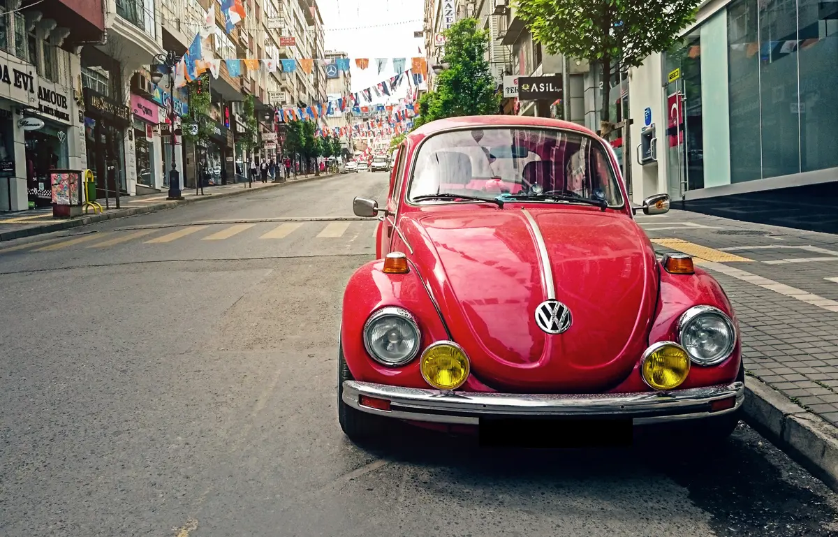 A red VW Beetle parked at the side of a city street
