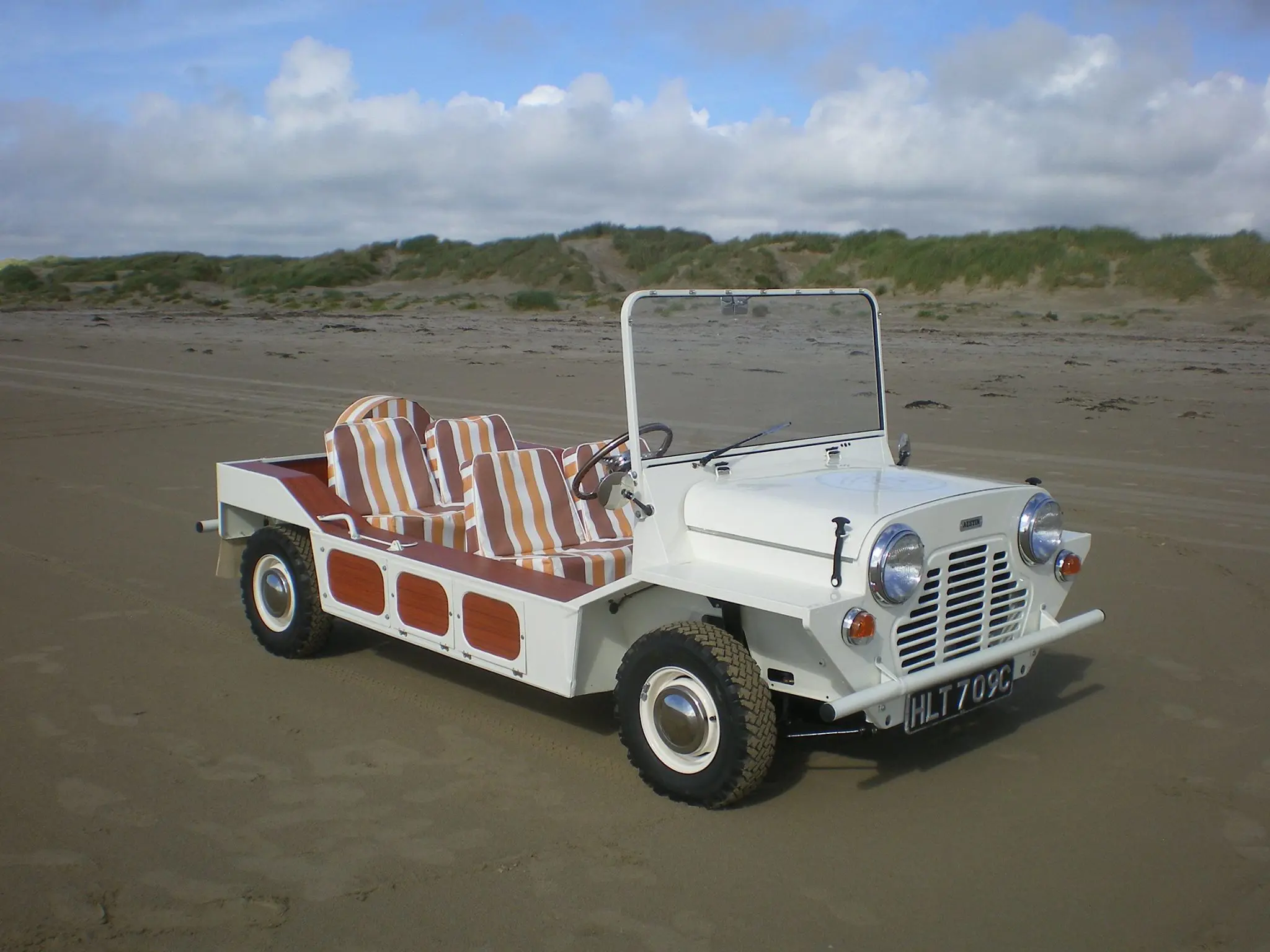 A white Mini Moke parked on a sandy beach