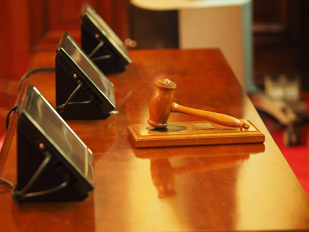 A desk at an auction house with three screens and a gavel on top