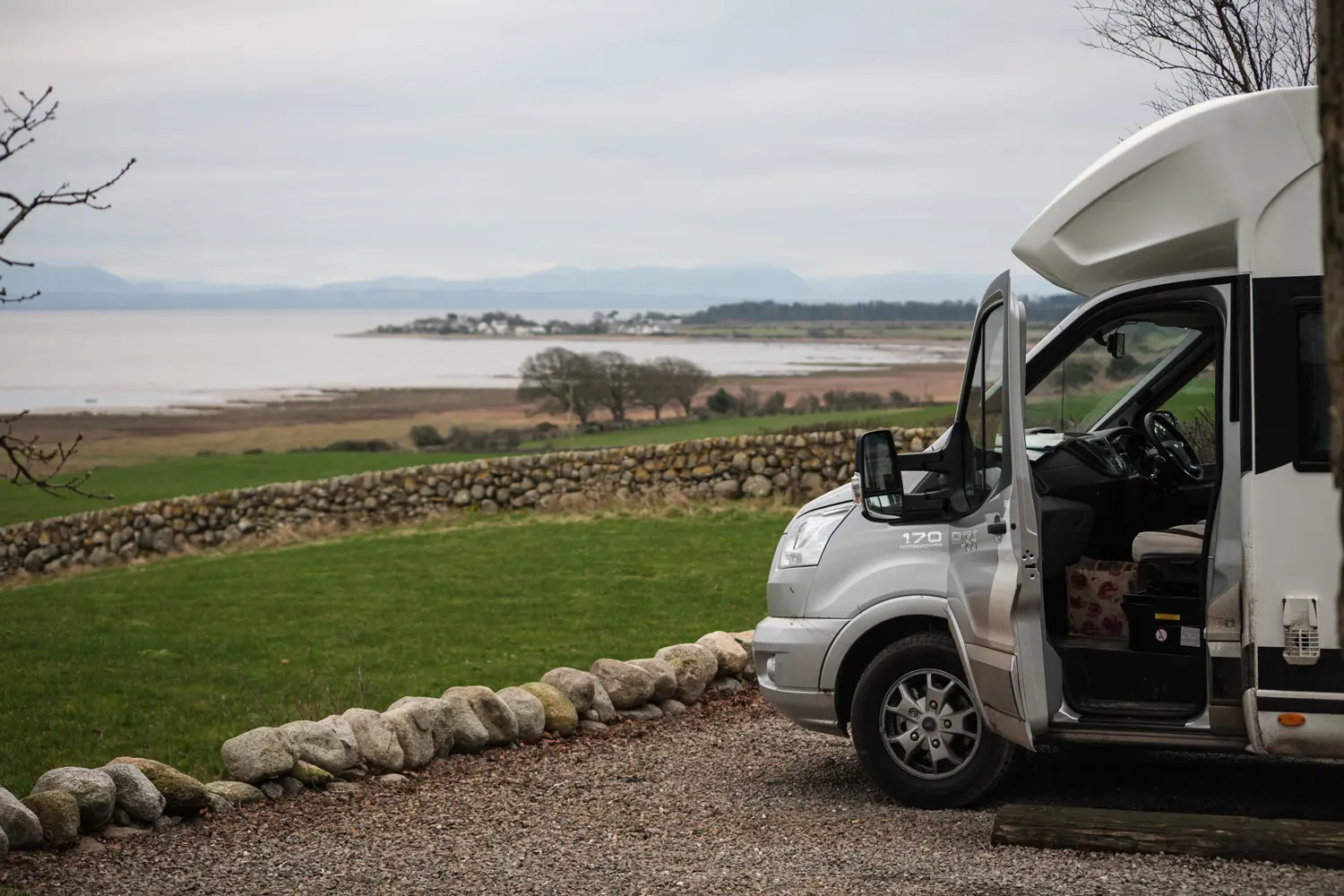 A motorhome with its door open next to a lake