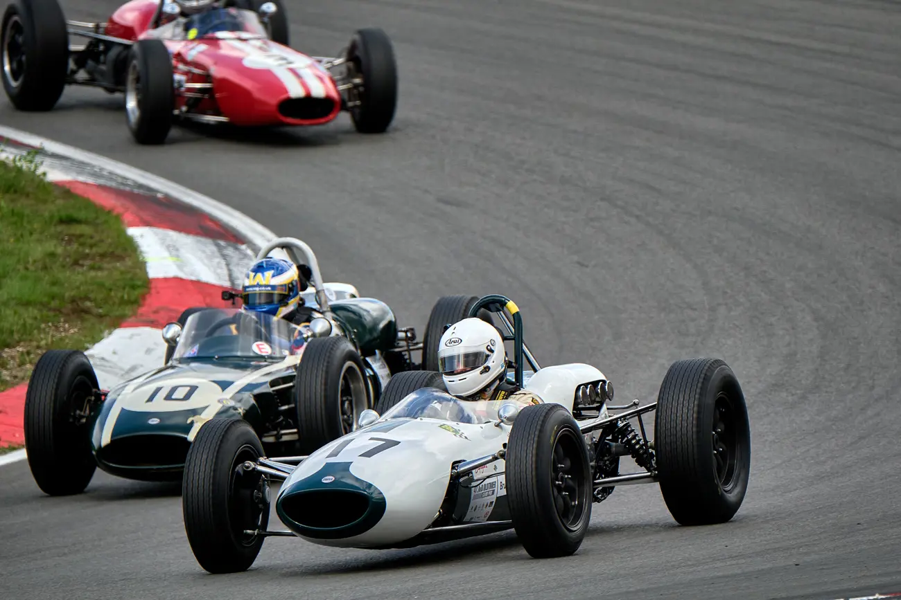 Vintage formula 1 cars racing round a corner of a race track