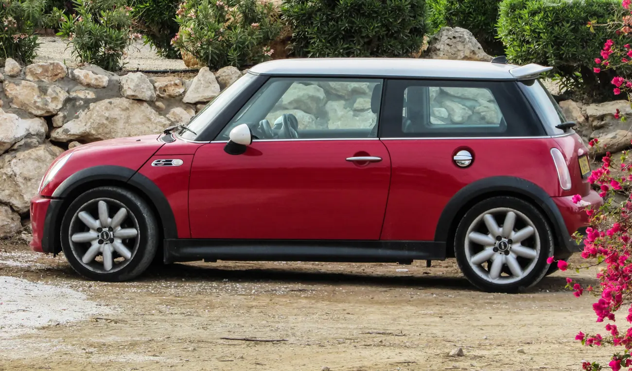 An early 2000's red Mini Cooper parked on a driveway