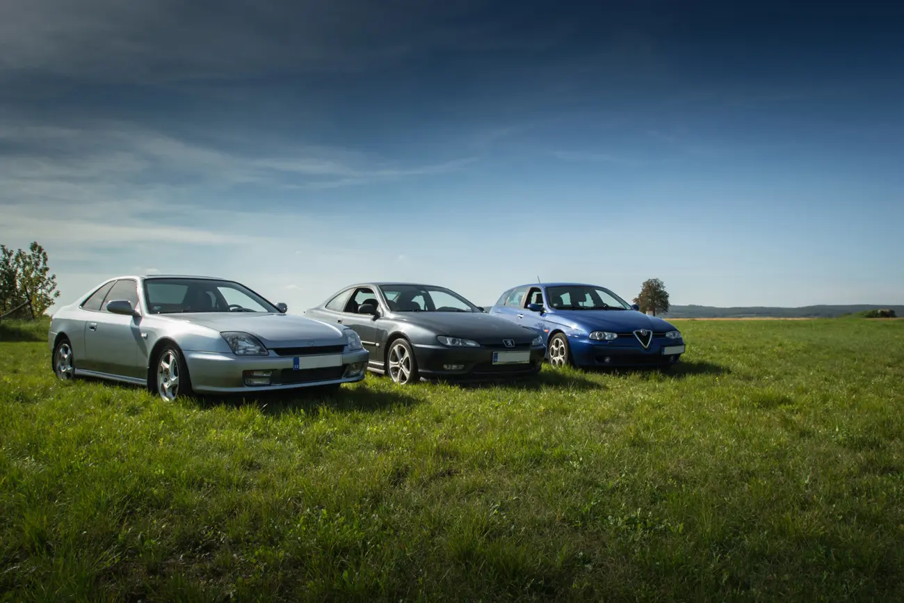 Three modern classic cars parked in a field