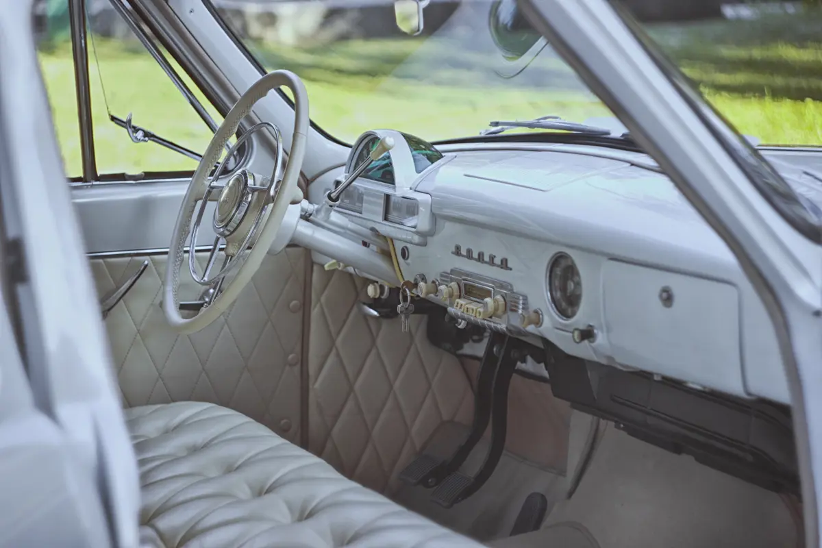 A left-hand drive classic car with a white luxury interior