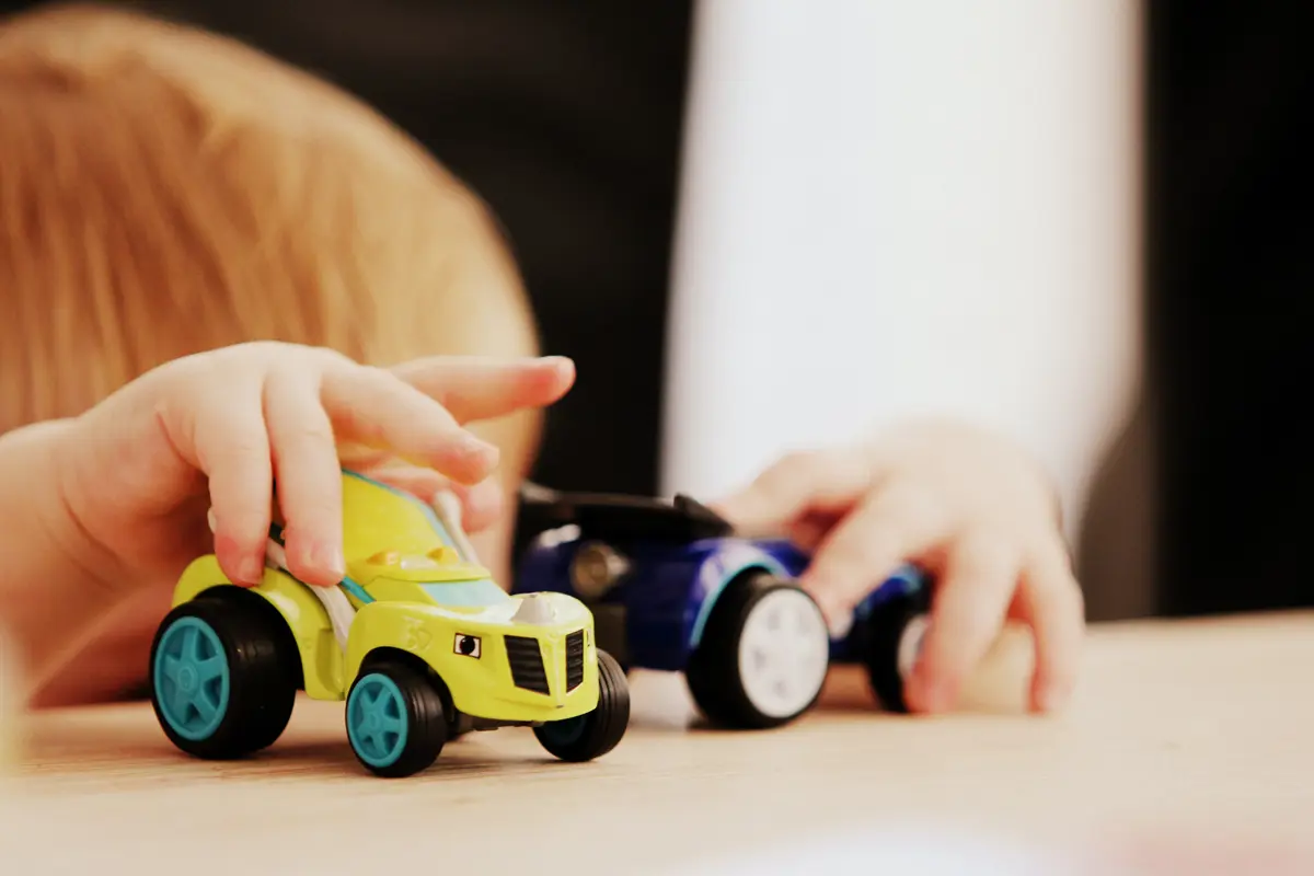 A child playing with two toy cars