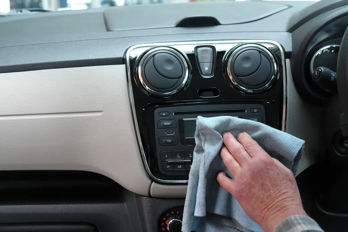 A person using a cloth to clean the dashboard of their motorhome
