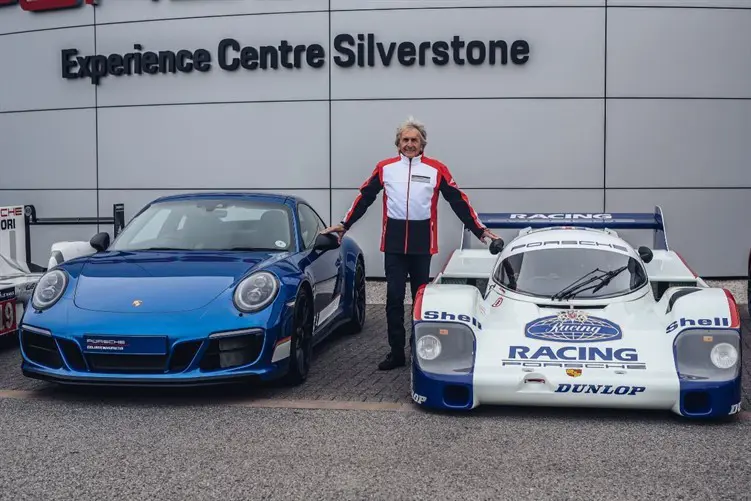 Derek Bell standing with two Porsche super cars at Sherborne Castle