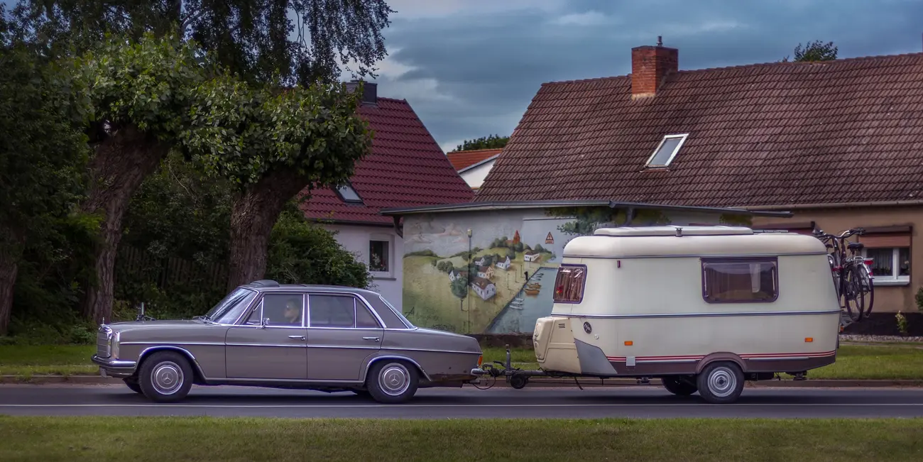 A classic car towing a caravan on holiday