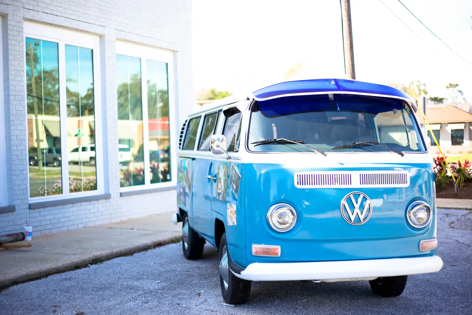 A blue vintage VW campervan parked in-front of a house on a sunny day