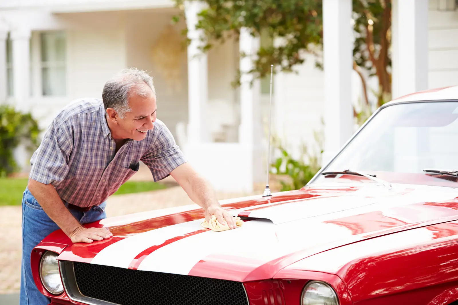 A man cleaning a classic mustang on his driveway