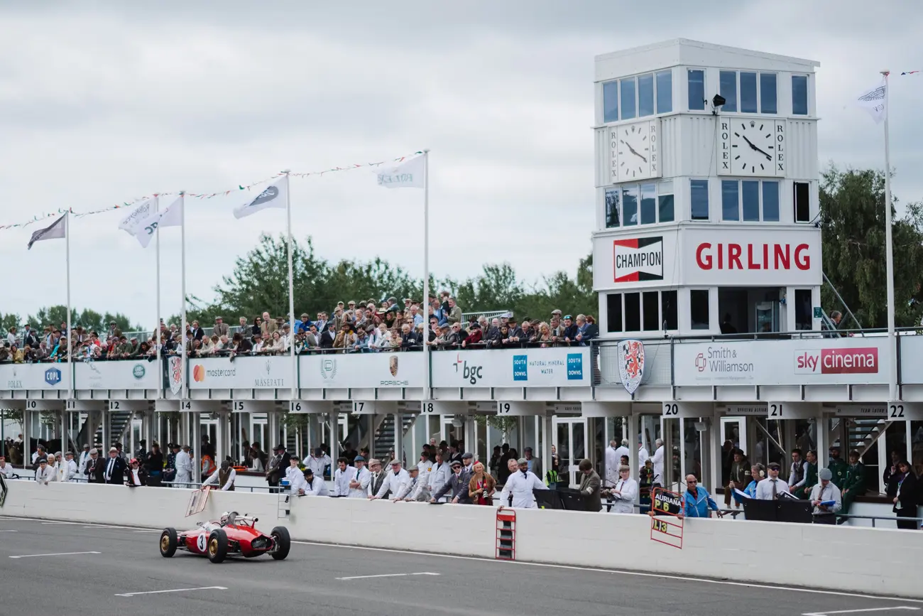 A race car driving past a stand at Goodwood racetrack