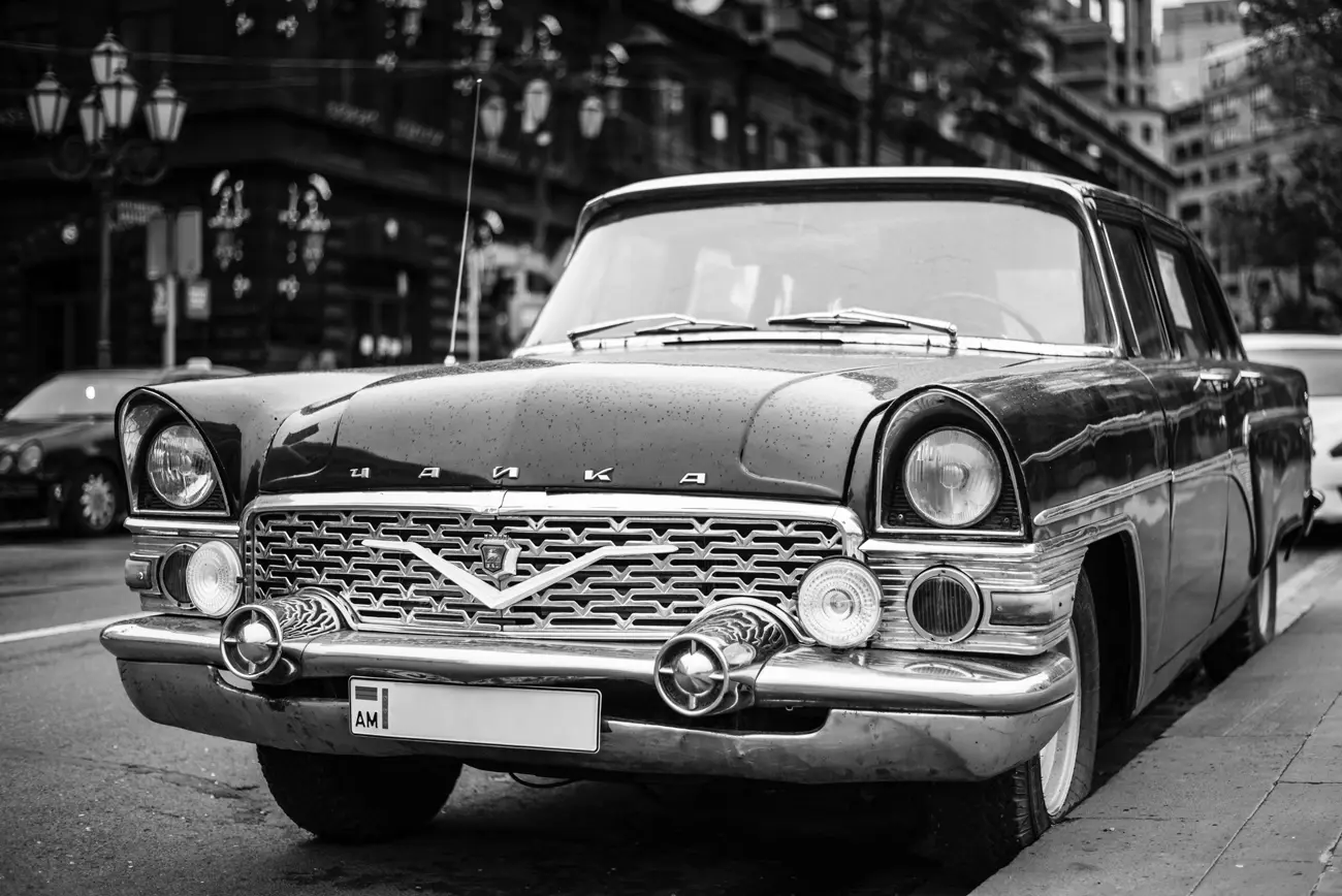 A GAZ Volga M21 parked at the side of a Russian road in black and white