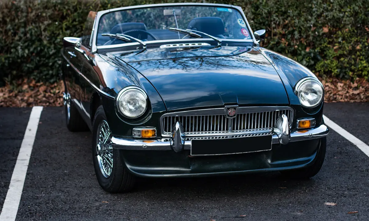 An MGB roadster parked in a parking bay with the roof down